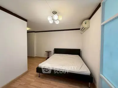 Spacious bedroom with modern lighting and air conditioning, featuring a minimalist design and wooden flooring.