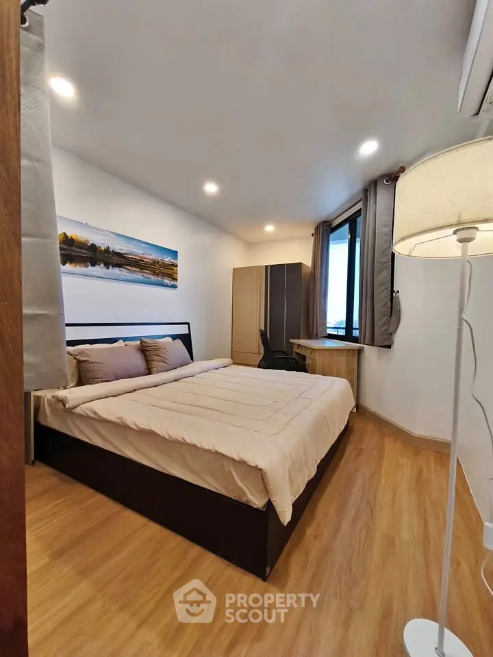 Cozy modern bedroom with wooden flooring and large window