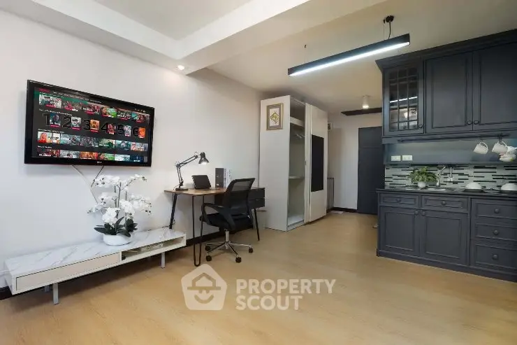 Modern living room with stylish decor and open kitchen layout, featuring sleek cabinetry and contemporary lighting.