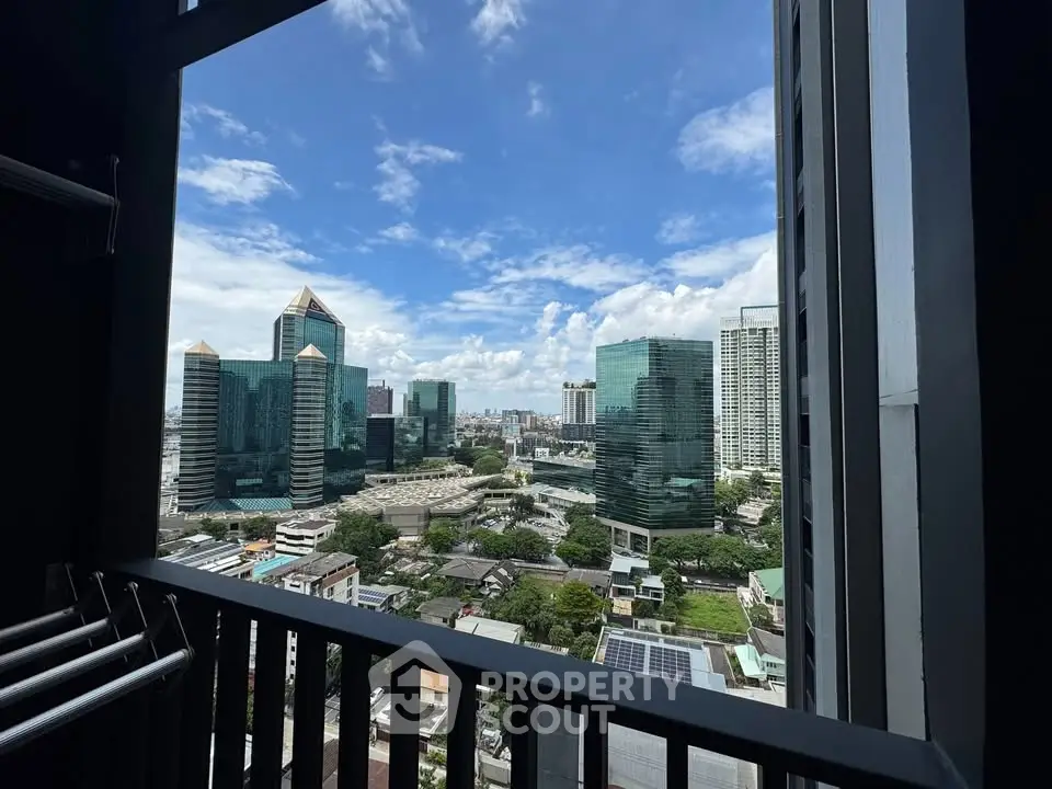 Stunning cityscape view from a high-rise balcony with modern skyscrapers under a clear blue sky.