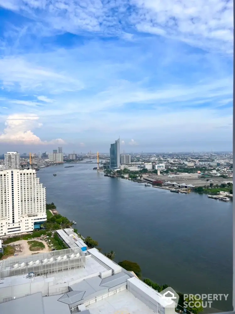 Stunning river view from high-rise building showcasing city skyline and blue sky.