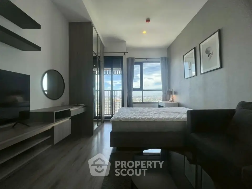 Modern bedroom with large window offering stunning city view, sleek furniture, and contemporary decor.