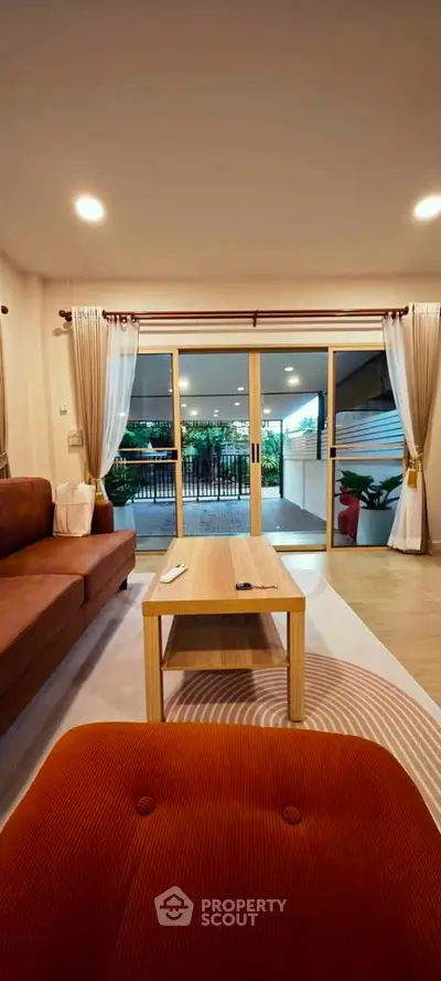 Spacious living room with elegant decor and large sliding doors opening to a lush garden view.