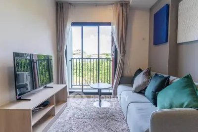 Modern living room with cozy sofa, TV, and balcony view in stylish apartment.
