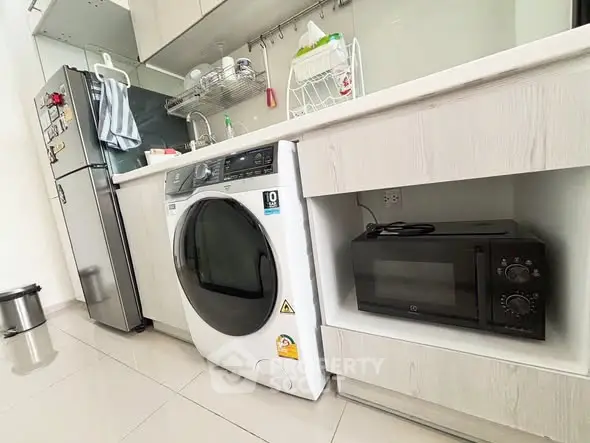 Modern kitchen with sleek appliances including washing machine and microwave, perfect for urban living.