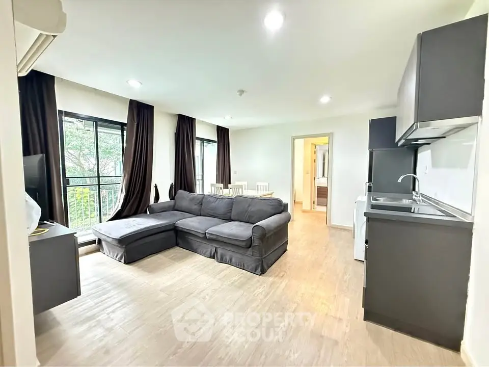 Modern living room with open kitchen and large windows in a stylish apartment.