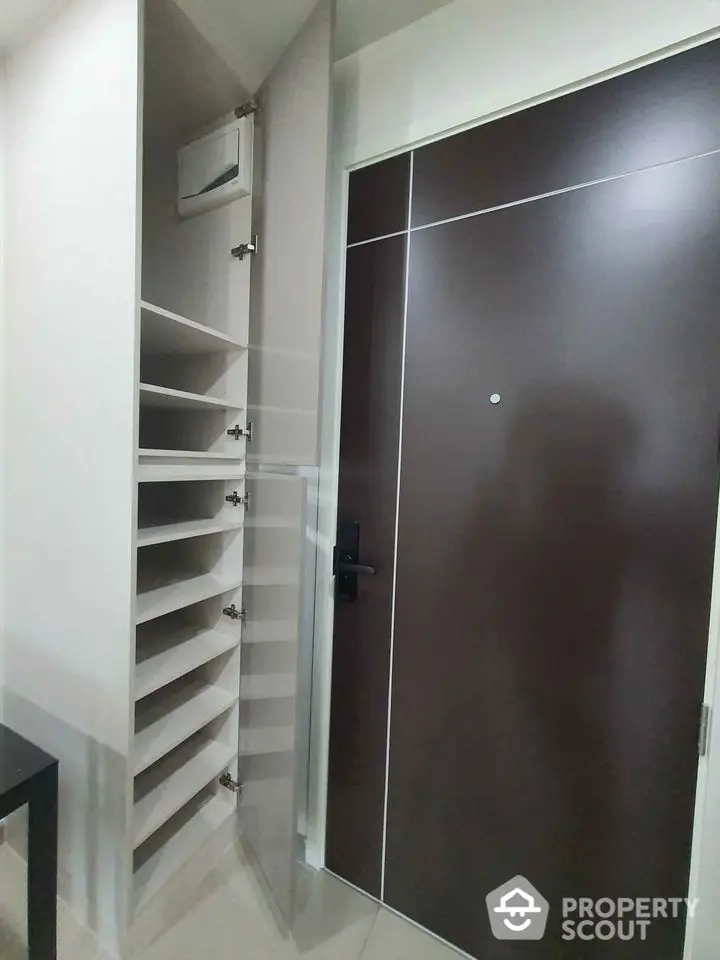 Modern apartment entrance with sleek storage shelves and elegant door design.