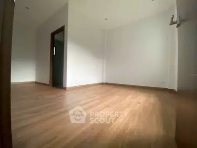 Spacious empty room with wooden flooring and white walls, ideal for customization.