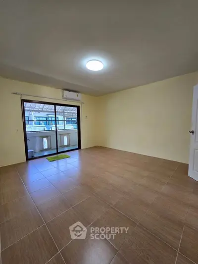 Spacious empty room with tiled flooring and balcony access, ideal for customization.