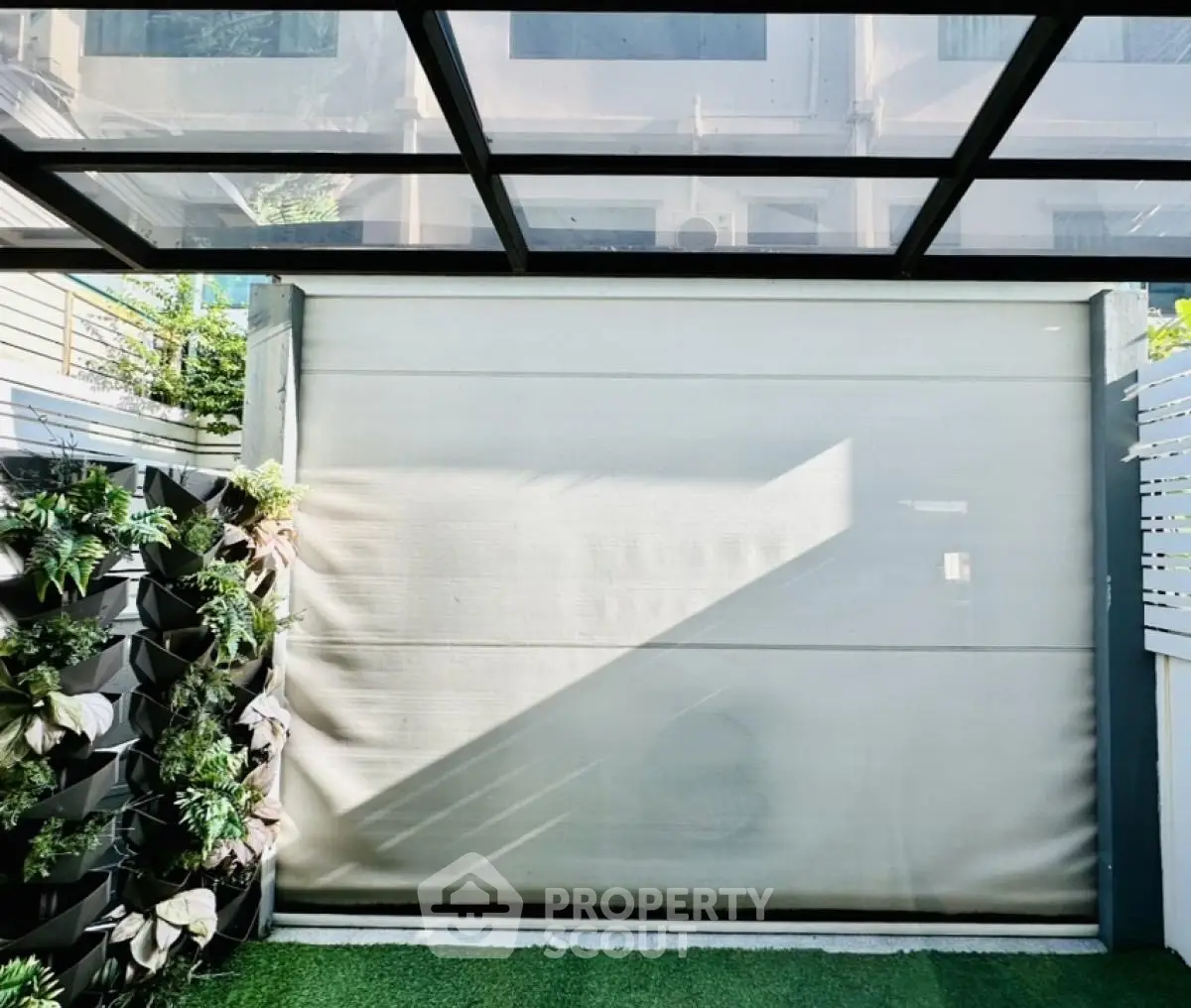 Modern outdoor garden space with vertical plant wall and glass roof.