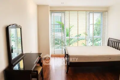 Spacious bedroom with elegant wooden furniture and large windows offering natural light.