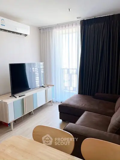 Modern living room with sleek TV setup and cozy brown sofa, featuring natural light from large window.