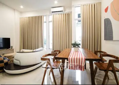 Modern living room with stylish furniture and natural light, featuring a cozy seating area and elegant dining table.