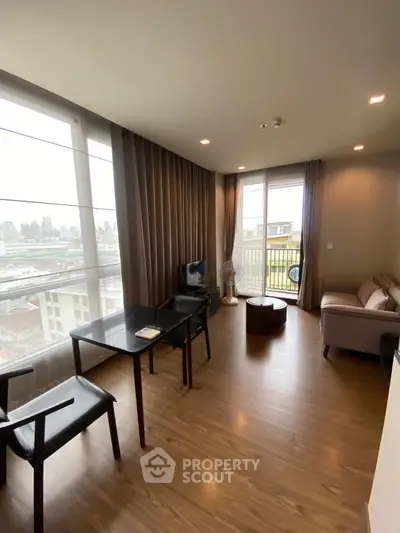 Modern living room with city view, featuring sleek furniture and large windows for natural light.