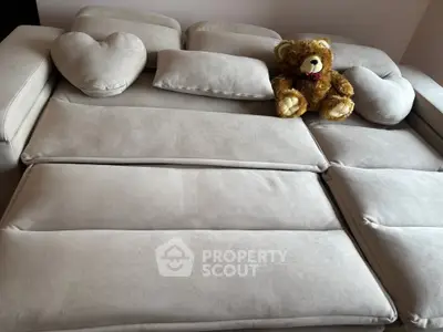 Cozy living room with plush beige sofa and cute teddy bear accent, perfect for relaxation.