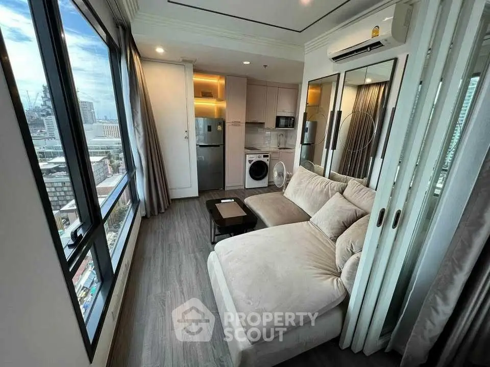 Modern living room with city view, featuring cozy sofa, washing machine, and sleek kitchen appliances.