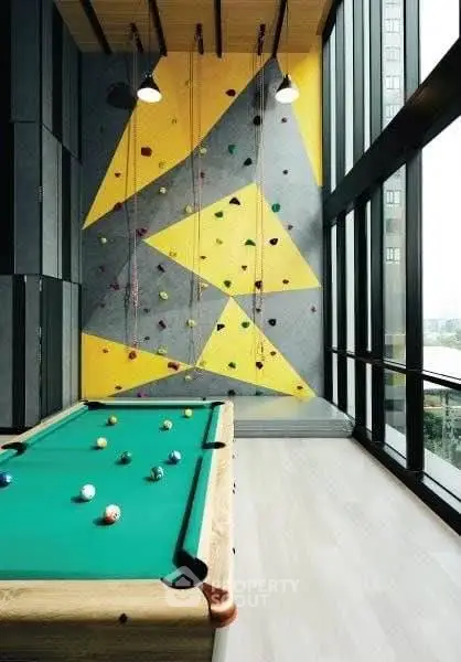 Modern recreational room with pool table and climbing wall in luxury apartment building.
