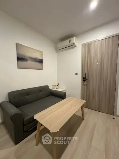 Cozy living room with modern sofa and wooden coffee table, featuring minimalist decor.