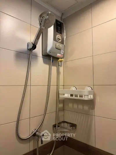 Modern bathroom with electric shower and tiled walls, perfect for a cozy home.