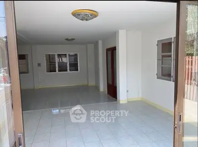 Spacious open-plan living area with tiled flooring and ample natural light.