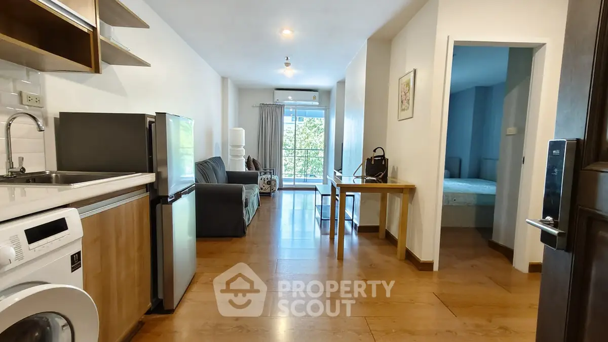 Modern apartment interior with open layout, featuring kitchen, living area, and bedroom with natural light.