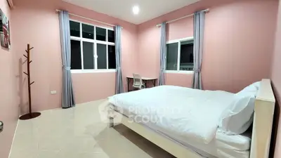 Spacious bedroom with pink walls and large windows, featuring a cozy bed and study desk.