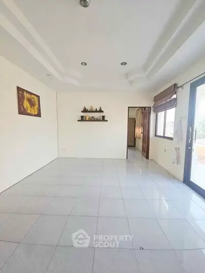 Spacious empty living room with large windows and tiled flooring, ready for customization.