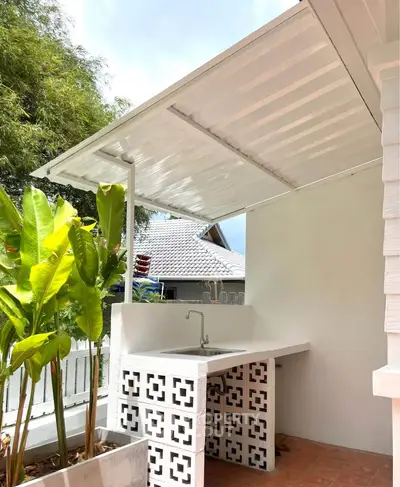Charming outdoor kitchen with modern sink and stylish design, perfect for entertaining in a cozy backyard.
