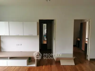 Spacious modern living room with wooden flooring and built-in storage cabinets.