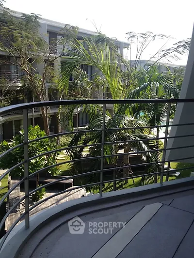 Luxurious balcony view overlooking lush garden and modern architecture in a serene residential complex.