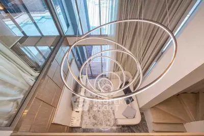 Stunning modern living room with spiral staircase and floor-to-ceiling windows overlooking pool area.