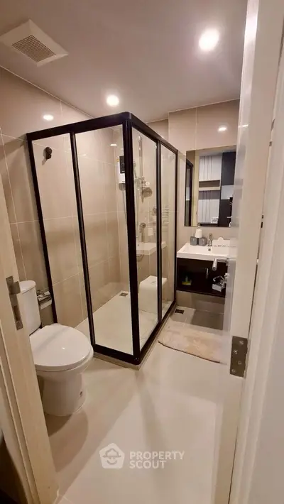 Modern bathroom with glass shower and sleek fixtures in contemporary apartment.