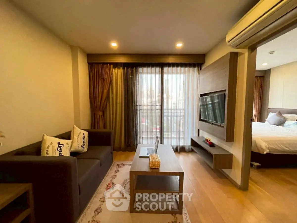 Modern living room with cozy sofa, flat-screen TV, and balcony view in stylish apartment.
