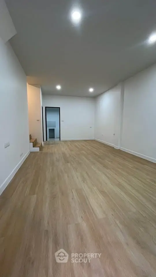 Spacious empty room with wooden flooring and recessed lighting, ideal for customization.