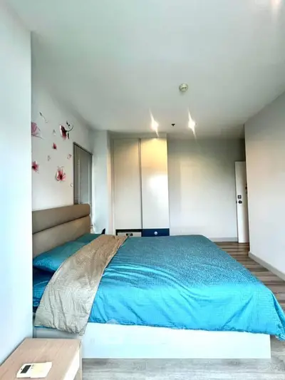 Spacious bedroom with modern decor and blue bedding in a stylish apartment.
