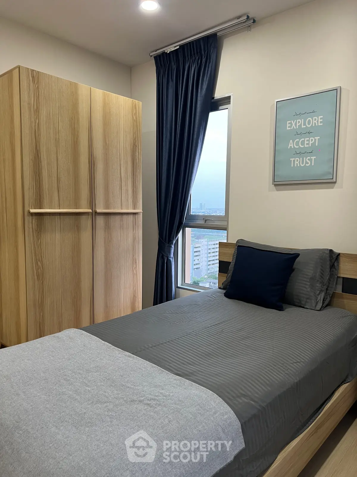 Cozy bedroom with modern decor, featuring a single bed, wooden wardrobe, and a window with city view.
