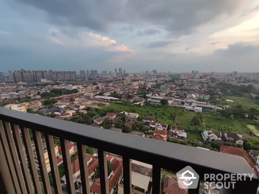 Stunning cityscape view from high-rise balcony at sunset, showcasing urban skyline and lush greenery.