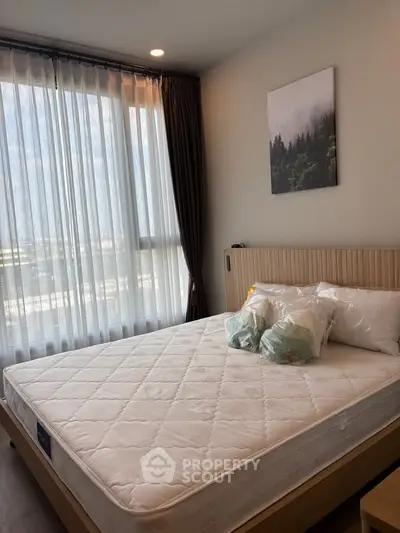Modern bedroom with large window and stylish decor in a bright apartment.