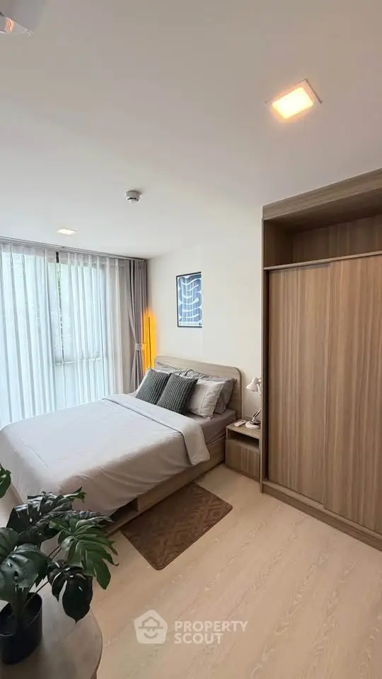 Modern bedroom with large window and stylish decor in a cozy apartment.
