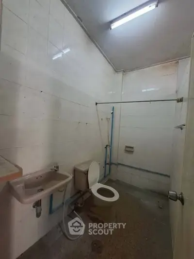Basic bathroom with toilet, sink, and shower area in need of renovation.