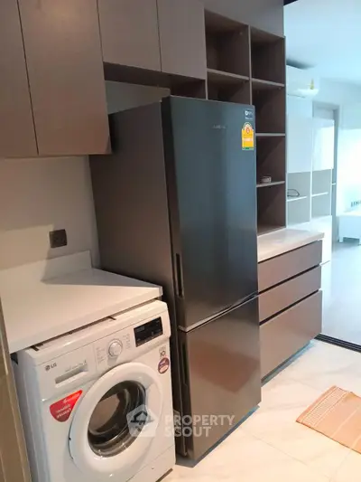 Modern kitchen with sleek appliances including fridge and washing machine, stylish cabinetry, and elegant flooring.