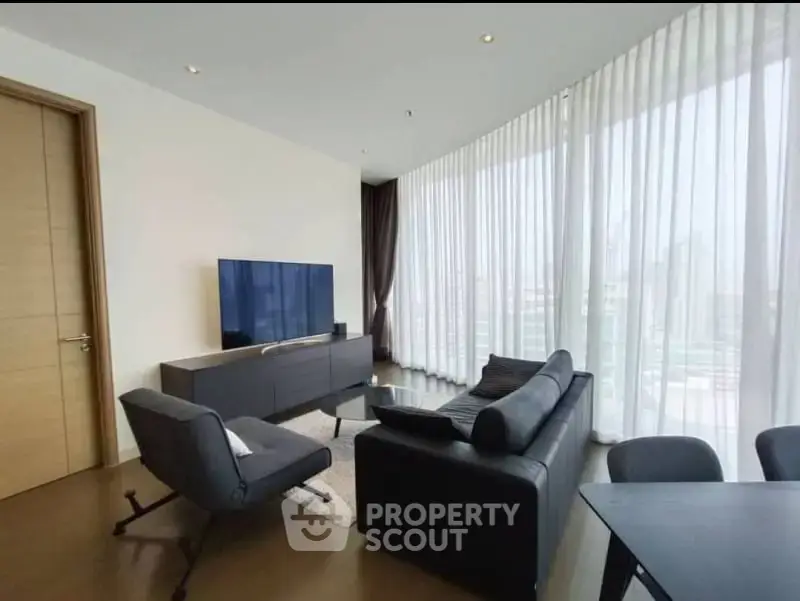 Modern living room with floor-to-ceiling windows and sleek furniture in a high-rise apartment.