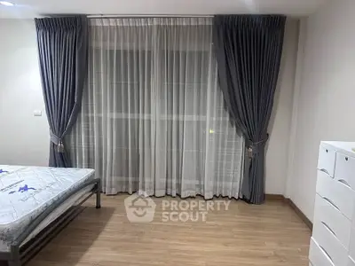 Spacious bedroom with elegant curtains and wooden flooring