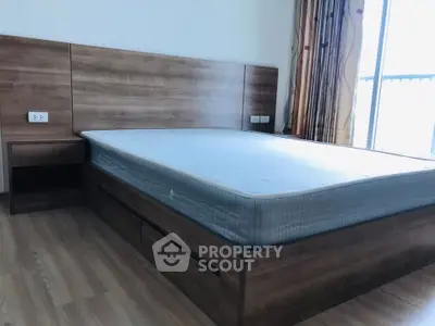 Spacious bedroom with wooden flooring and large window for natural light