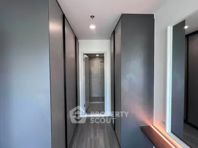 Modern hallway with sleek design leading to a bathroom, featuring contemporary finishes and ample storage.