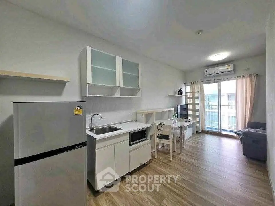 Modern open-plan living room with kitchen, featuring sleek appliances and bright natural light.