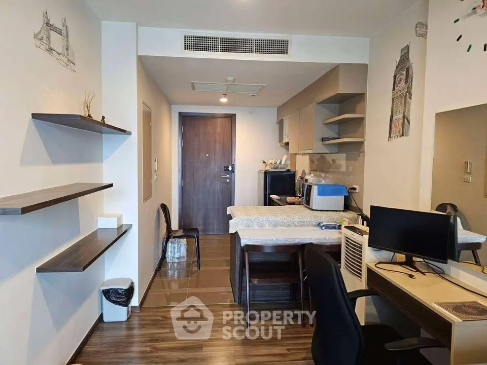 Modern apartment interior with open layout, featuring a compact kitchen and stylish workspace.