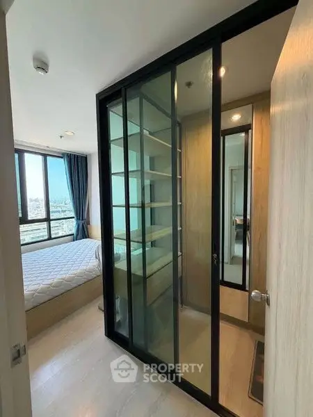 Modern bedroom with glass partition and city view, featuring sleek design and natural light.