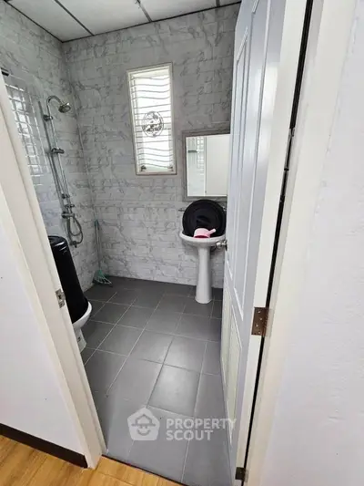 Compact bathroom with modern shower and washing machine in a sleek tiled design.