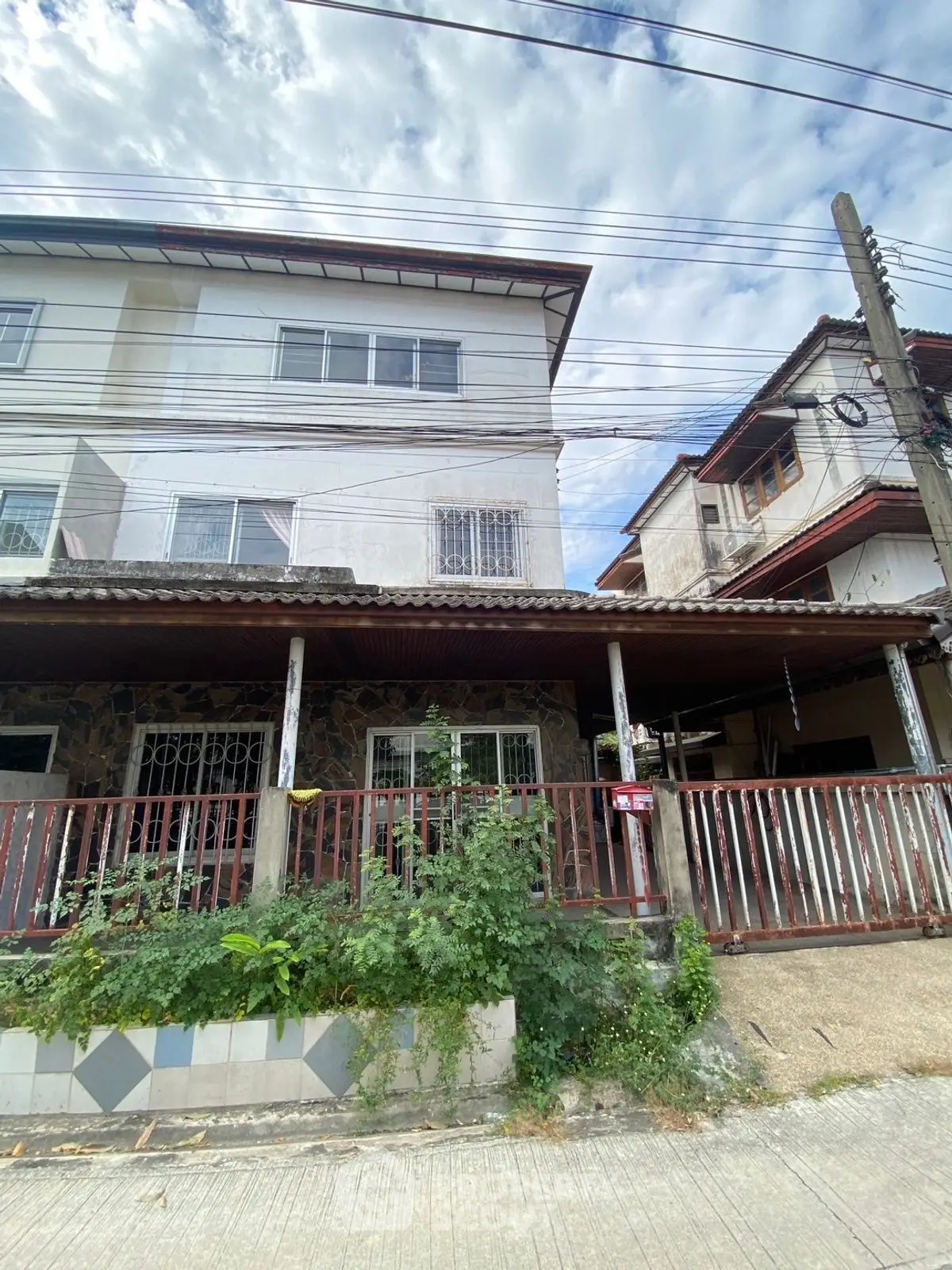 Charming multi-story residential building with rustic facade and lush greenery in urban setting.